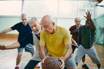 Fototapeta premium Senior men playing competitive basketball in indoor gym