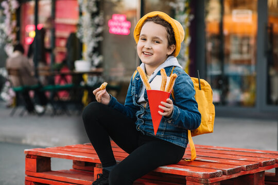 Cute little girl eating traditional Spanish treat street fast food churros. Food delivery or take away food concept.