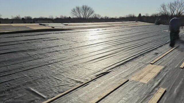 Watch large sheets of underlayment unroll to cover roof deck for fast weatherproofing in a timelapse process