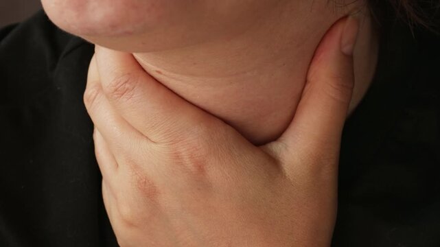 Woman with sore throat touching neck with a hand, suffer from painful swallowing, tonsillitis, irritation or thyroid gland salivary disease