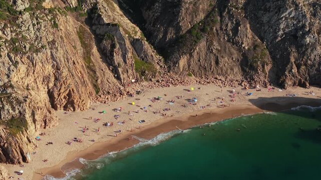 Praia da Ursa beach at Sintra-Cascais Natural Park in Portugal, washed by waters of Atlantic Ocean. People enjoying summer vacations at beach during sunny day.