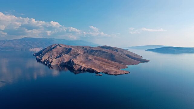 Elevated view of Prvić island with rugged cliffs and smooth hills rising from the Adriatic Sea. Mediterranean seascape highlighting isolation and natural coastal formations near Krk island, Croatia