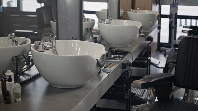 Empty modern barbershop interior. Several barbershop chairs, washbasins and workstations with hairdressers equipment and tools