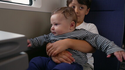 Older brother holding baby sibling on train, shared journey, travel bonding moment, childhood...