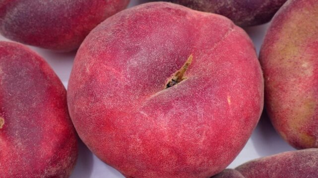 Fresh red flat peaches circle rotation close up