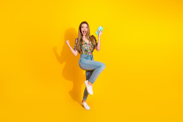 Young stylish woman jumps for joy and selfies on a bright yellow background