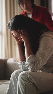 Sad Asian woman listening to accusations of angry husband, psychological abuse
