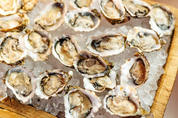 Fresh raw oysters served on crushed ice in wooden tray
