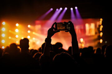 Person recording a music concert on a smartphone in a crowd