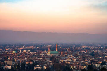 Obraz premium Panoramic high-angle view of Vicenza city skyline at sunset featuring the Basilica Palladiana and Torre Bissara against the Venetian Prealps, Italy 08.01.2026