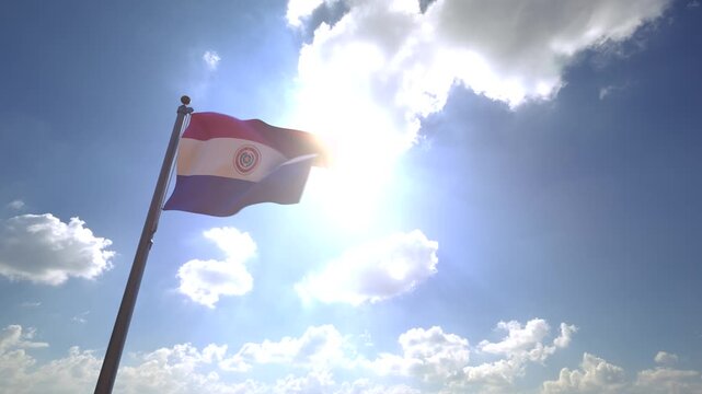 Paraguay Flag waving on a Flagpole from a Moving Angle in front of a blue sky with clouds	
