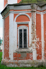 Obraz premium A window in the arched opening of the brick wall of a medieval church in Pereslavl-Zalessky, in the process of restoration