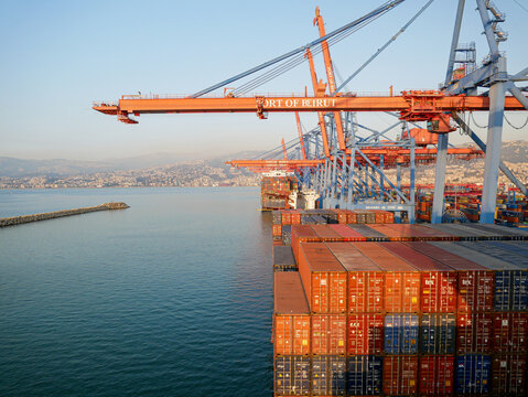 Beirut, Lebanon - 05.15.2025 - Large container cranes loading CMA CGM cargo ship at container terminal in Port of Beirut with stacked containers and Mediterranean sea view.