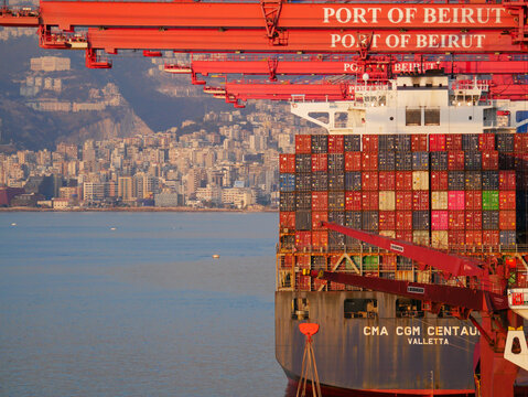 Beirut, Lebanon - 05.15.2025 - Large container cranes loading CMA CGM cargo ship at container terminal in Port of Beirut with stacked containers and Mediterranean sea view.