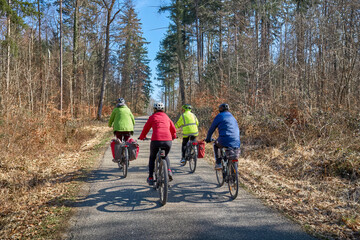 Fototapeta premium Group of active seniors enjoying a bicycle tour on a sunny spring day in the Swabian Forest, Germany. Friends cycling together through nature, promoting healthy lifestyle, recreation, and outdoor