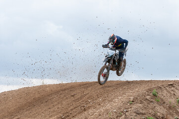 Obraz premium Unrecognized athlete riding a sports motorbike jumping on the air on a motocross race. Fast speed extreme sport.