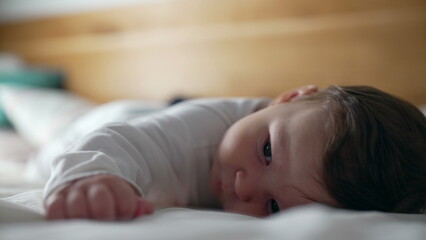 Baby lying on stomach, playful expression, smiling while lifting head, early development, tummy time, strengthening muscles, childhood curiosity, joyful moment, home setting