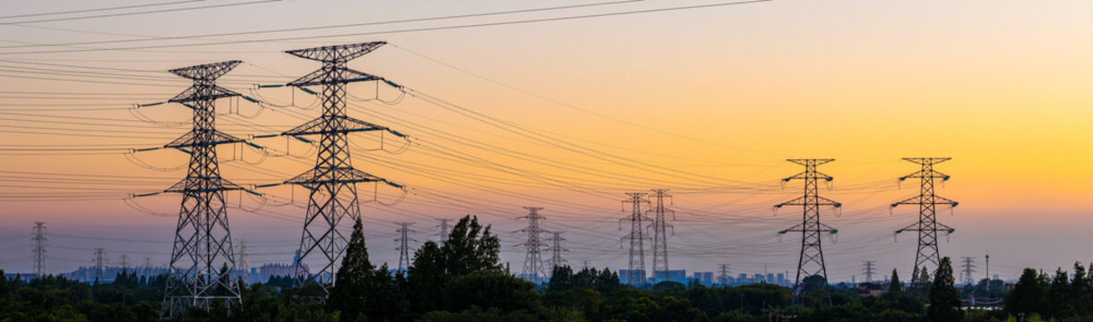 High voltage electricity pylons and transmission lines at sunset. Power grid and energy infrastructure industry concept.