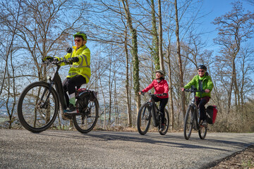Fototapeta premium Group of active senior women enjoying a bicycle tour on a sunny spring day in the Swabian Forest, Germany. Friends cycling together through nature, promoting healthy lifestyle, recreation, and outdoor
