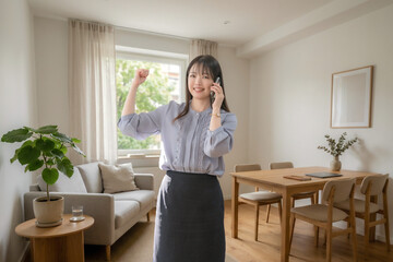 スマートフォンで電話しながら喜ぶ女性 © YUTO PHOTOGRAPHER