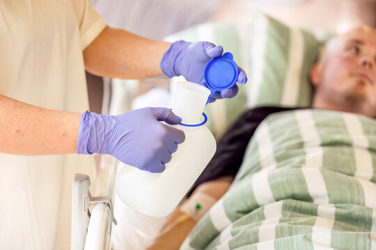 Nurse holding urine bottle for male patient in hospital bed, basic nursing care and hygiene assistance