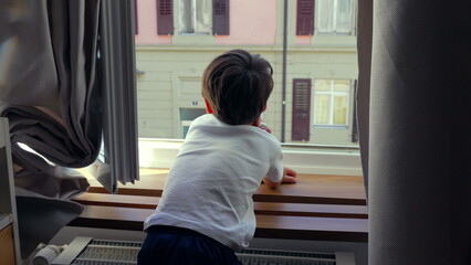 Young boy leaning on windowsill, gazing outside, deep in thought, quiet moment of reflection,...