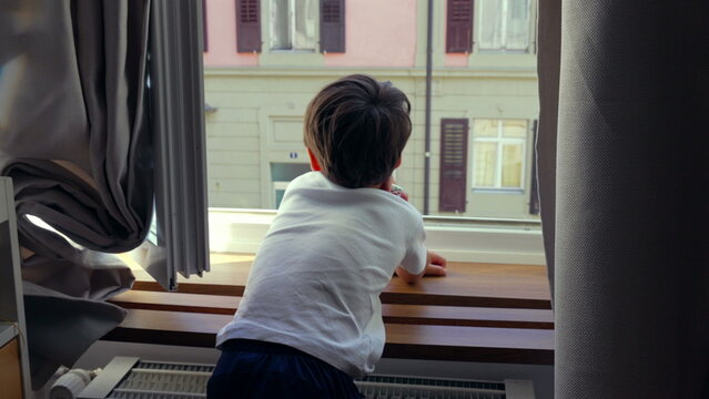 Young boy leaning on windowsill, gazing outside, deep in thought, quiet moment of reflection, childhood curiosity, urban home setting, observing city life, daydreaming