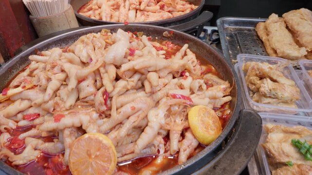 Traditional Chinese street food style spicy chicken feet stew with lemon slices and chili peppers served at a bustling night market food stall in Shanghai, showcasing authentic Asian street cuisine