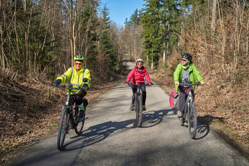 Fototapeta premium Group of active senior women enjoying a bicycle tour on a sunny spring day in the Swabian Forest, Germany. Friends cycling together through nature, promoting healthy lifestyle, recreation, and outdoor