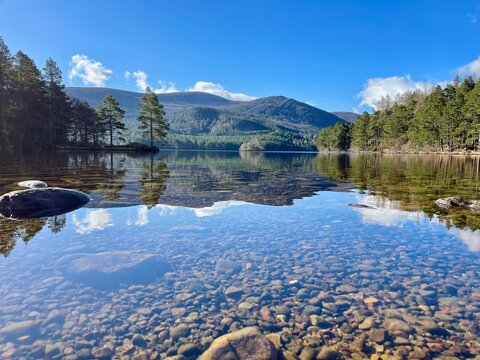 Scenic photo of Loch an Eilein with the Cairngorm Mountain in the background, in the Scottish Highlands, near Aviemore, United Kingdom