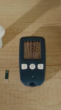 Vertical Screen: A glucometer displays a reading of 136 mg dL on a wooden table. This indicates a high blood sugar level. The setting includes test strips and a lancing device.