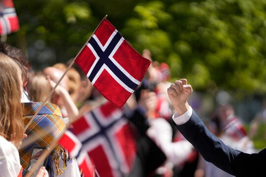 Crowd of people waving Norwegian flags and cheering a national celebration in Norway. Norwegian Constitution Day and national pride, representing Scandinavian culture, patriotism, cultural traditions.