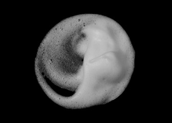 White cosmetic foam or soap bubbles texture isolated on black background. Abstract cleaning mousse...