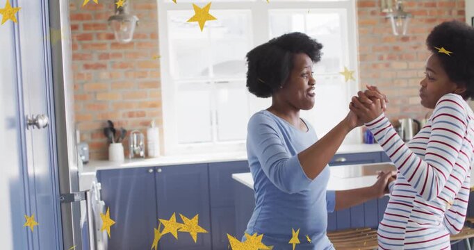 Mother holding daughter's hands guiding health dance steps in kitchen with animated stars floating