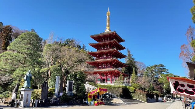 Five story red pagoda rising over stone statues and trees