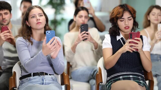Young learners sitting and scanning QR codes with smartphones in modern educational setting