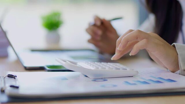  Female accountant working on financial investment on calculator, calculation, analysis of company income.