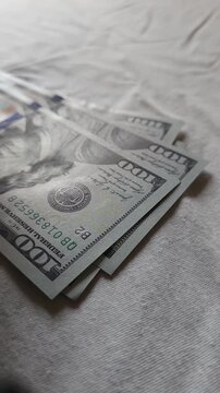 US dollar banknotes are being counted on grey background, closeup wide angle view.