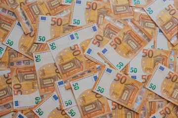 Dense array of 50 Euro bills in an artistic scatter. High-detail macro of orange European currency featuring Renaissance architecture, holograms, and watermarks