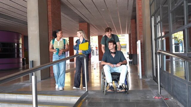 Diverse group of college students, including one in a wheelchair, walking together in an accessible university hallway after classes