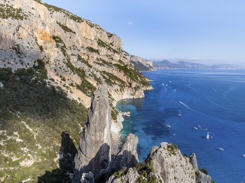 Picturesque rocky coast, cliffs with L'Aguglia pinnacle, blue sea and Cala Goloritz&eacute; beach, aerial view, Golfo di Orosei, Baunei, Sardinia, Italy