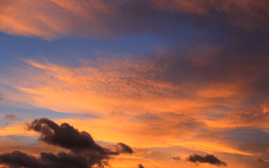 Obraz premium Dramatic sunset sky with vibrant orange and deep blue clouds creating a breathtaking natural spectacle