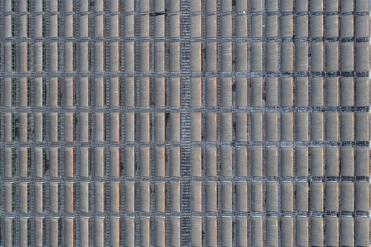 Aerial view of a grid of tightly packed, sun-drenched structures casting long shadows, a geometric dance of light and form unfolds, Rome, Lazio, Italy.