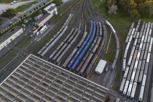 Aerial view of rows of trains and railroad tracks create geometric patterns, with industrial buildings adding a touch of starkness, Rome, Lazio, Italy.