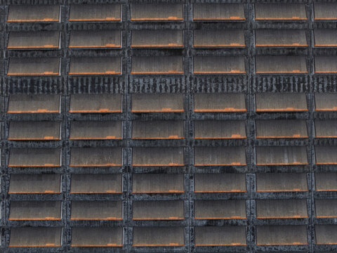 Aerial view of a building's facade displaying a rhythmic pattern of windows, their orange hues contrasting with the dark, textured concrete, Rome, Lazio, Italy.