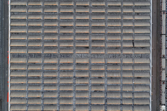 Aerial view of the rhythmic pattern of a vast industrial building's roof, a geometric tapestry woven with light and shadow, Rome, Lazio, Italy.