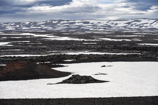 Snow-covered volcanic landscape with volcanic sand and petrified lava, crater of Askja volcano, Icelandic highlands, Iceland