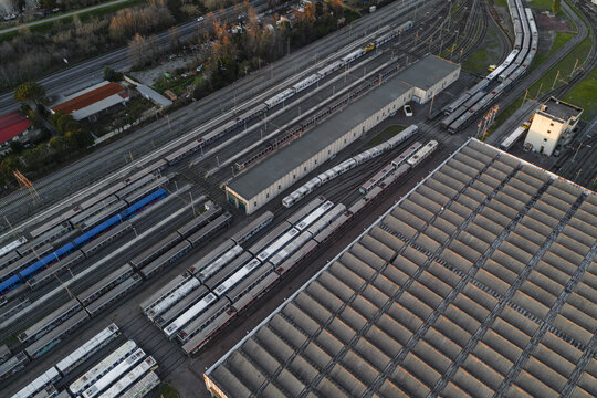 Aerial view of a sprawling railway yard glinting in the late afternoon sun, casting long shadows across the rows of trains and the complex infrastructure, Rome, Lazio, Italy.