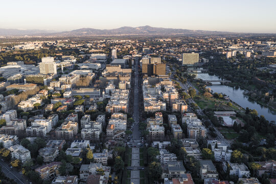 Aerial view of a symmetrical cityscape with orderly streets, buildings, and a river meandering through the right side, set against distant mountains, Rome, Lazio, Italy.