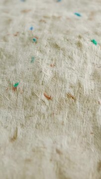 Vertical video: Moving cam refocusing across beige sheet in room, revealing blue green bits